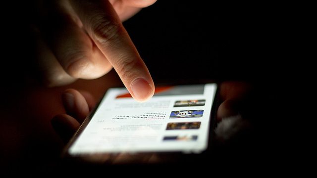 Image, Person selecting link to an article on a smartphone.