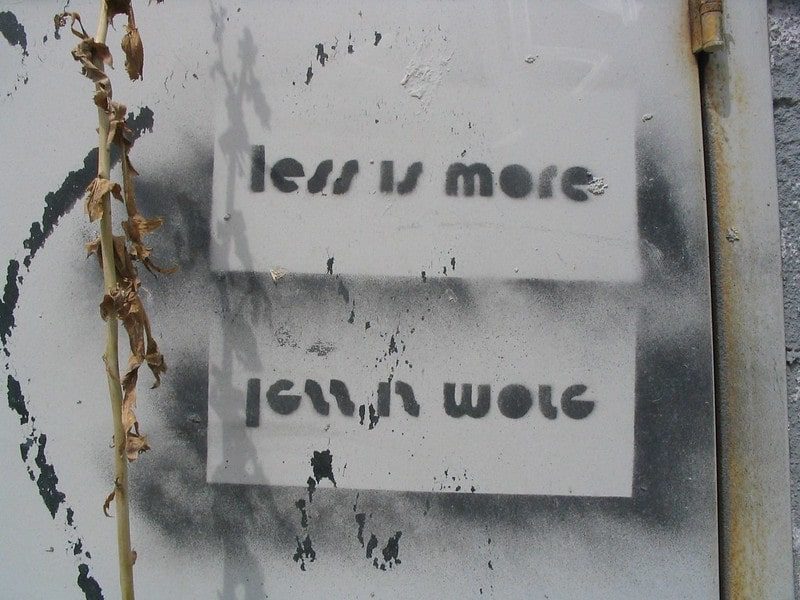 Less is more wording stenciled on a white wall 