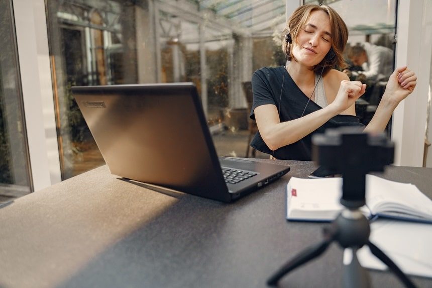 Image, person wearing headphones and doing a little dance in their seat in front of their laptop