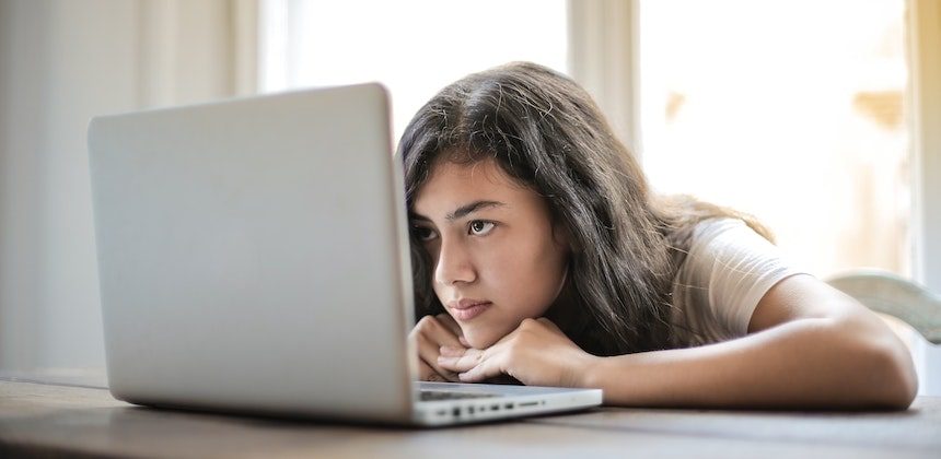 A woman looking thoughtful while sitting in front of a computer.