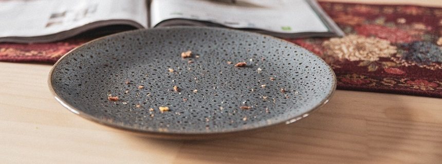 A few crumbs sit on an empty grey plate.