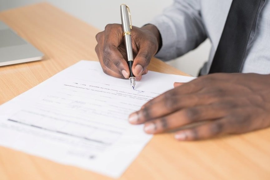 Person holding gray twist pen and signing a document 