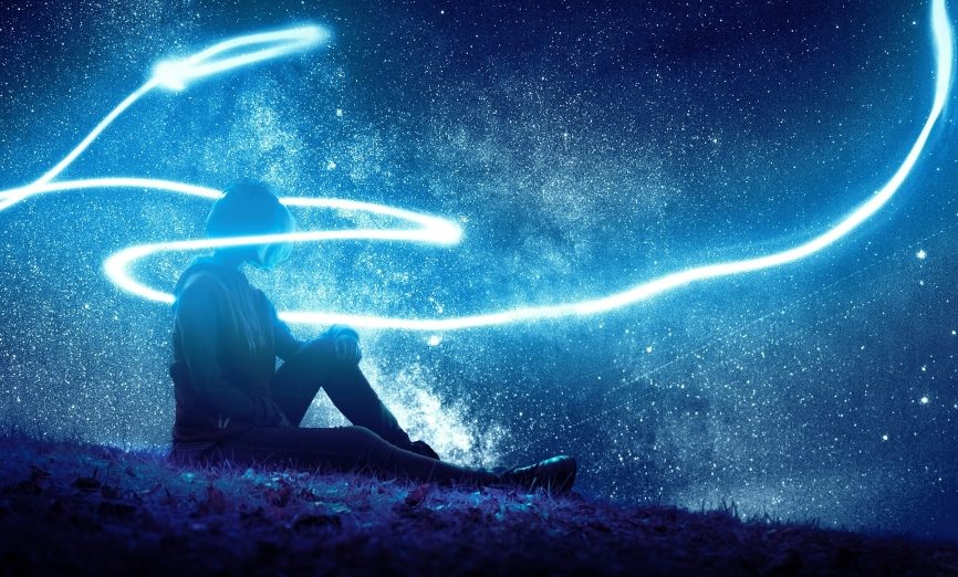 Person seated on grass with stars and bright lights surrounding them. 