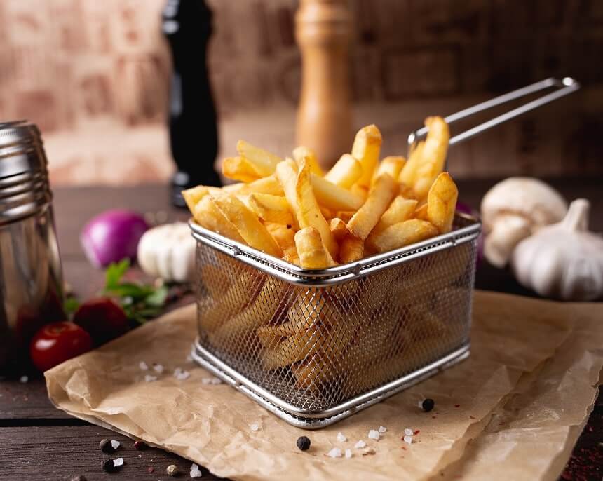 French fries cooked to golden brown, served in a small wire basket.