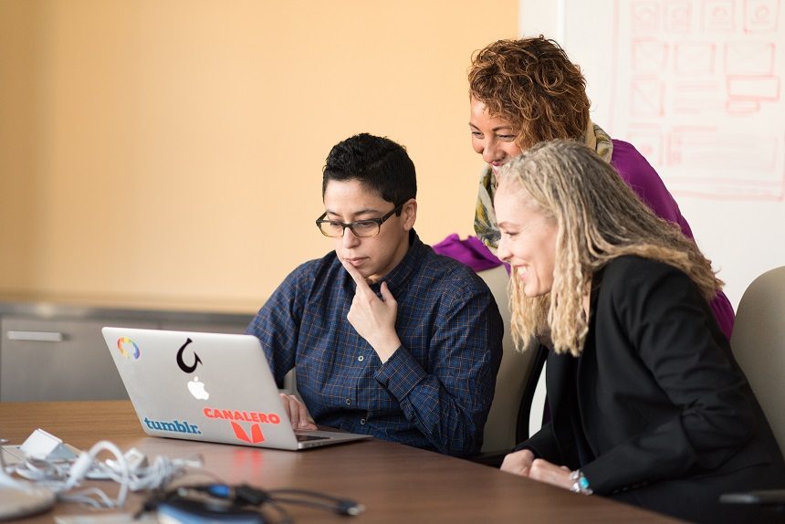 Image, two women and a man looking at a computer screen