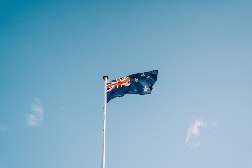 A New Zealand flag flying in a blue sky. New Zealand's Plain Language Act came into effect on 21 April 2023.