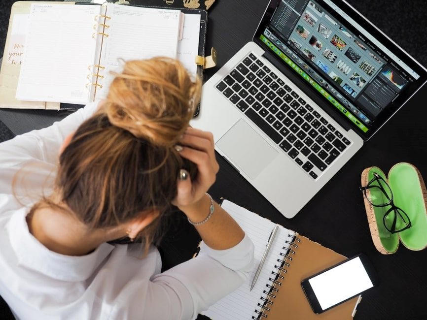 Woman sitting in front of Macbook, and a messy desk