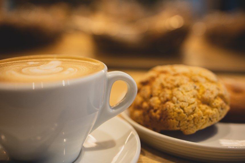 Cup of coffee with Anzac biscuit on a plate. 