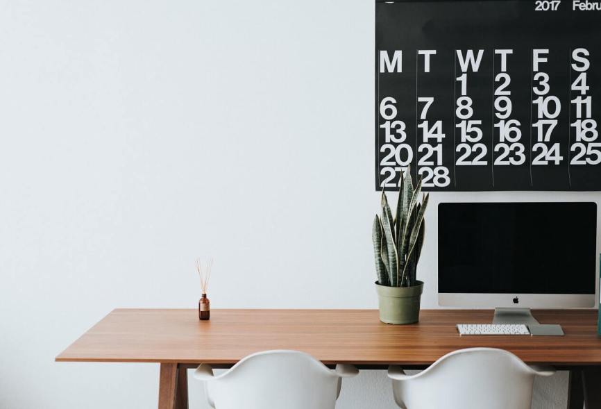 Image, Apple computer on a desk with two chairs and a plant with a calendar in the background