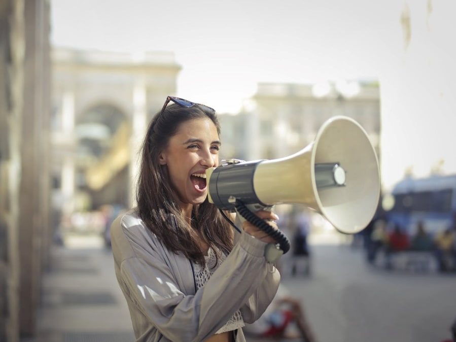 Cheerful young woman speaking into megaphone.