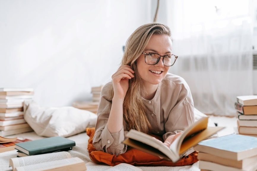 Person smiling surrounded by books 