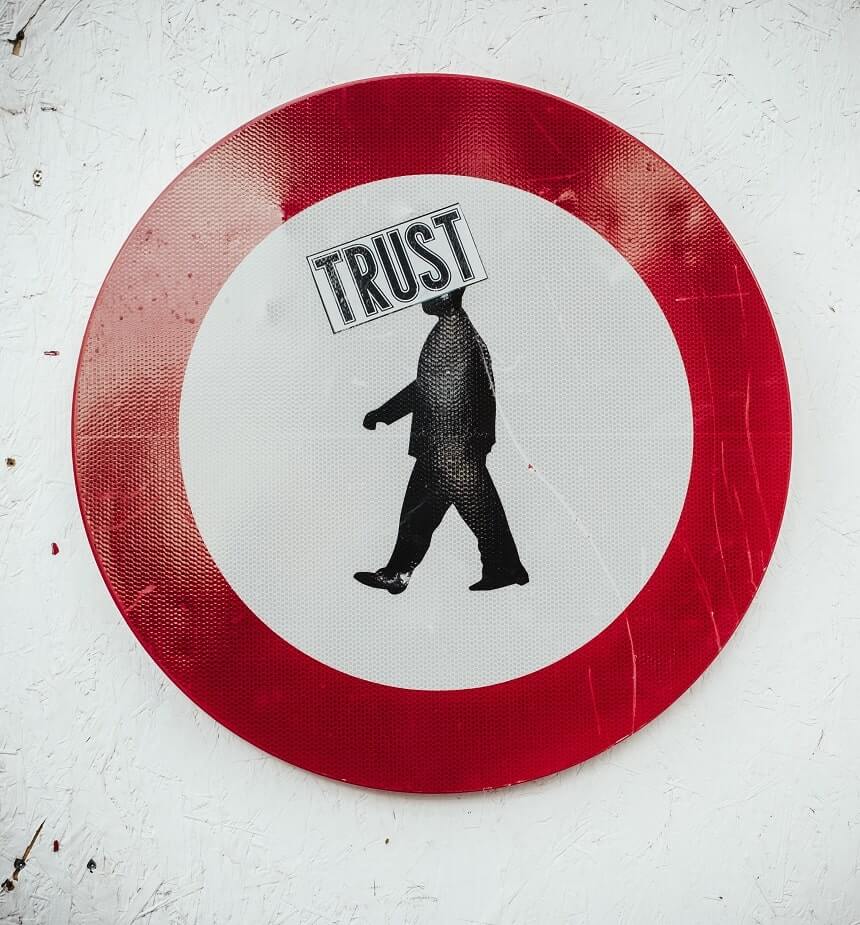 Image, reflective sign of a person inside a red circle with the word 'Trust' stamped over their head