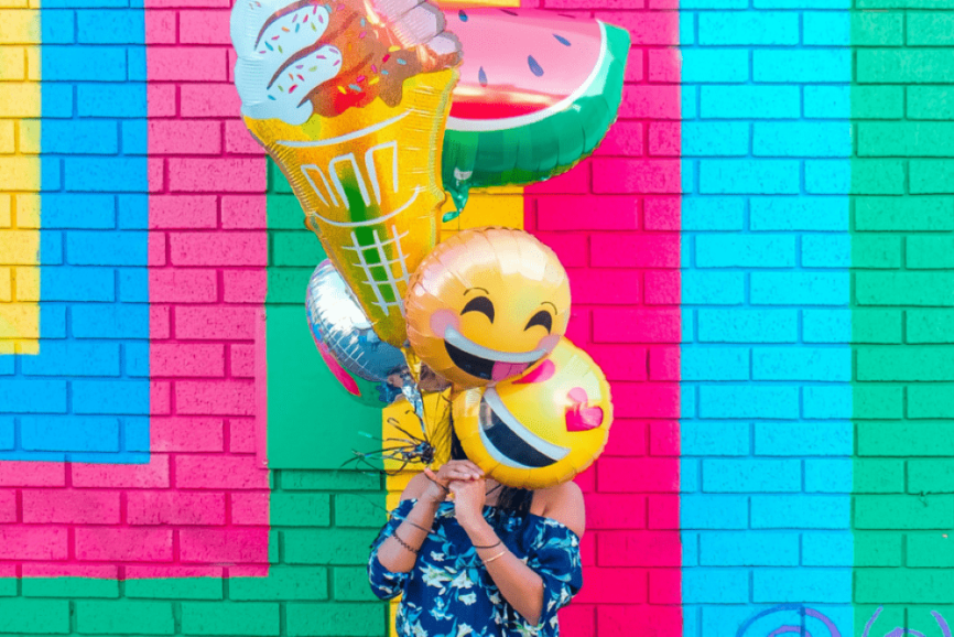 Woman covering her face with assorted ballons.