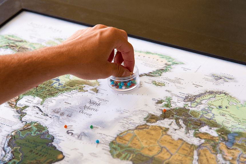 Hand placing push pins into world map